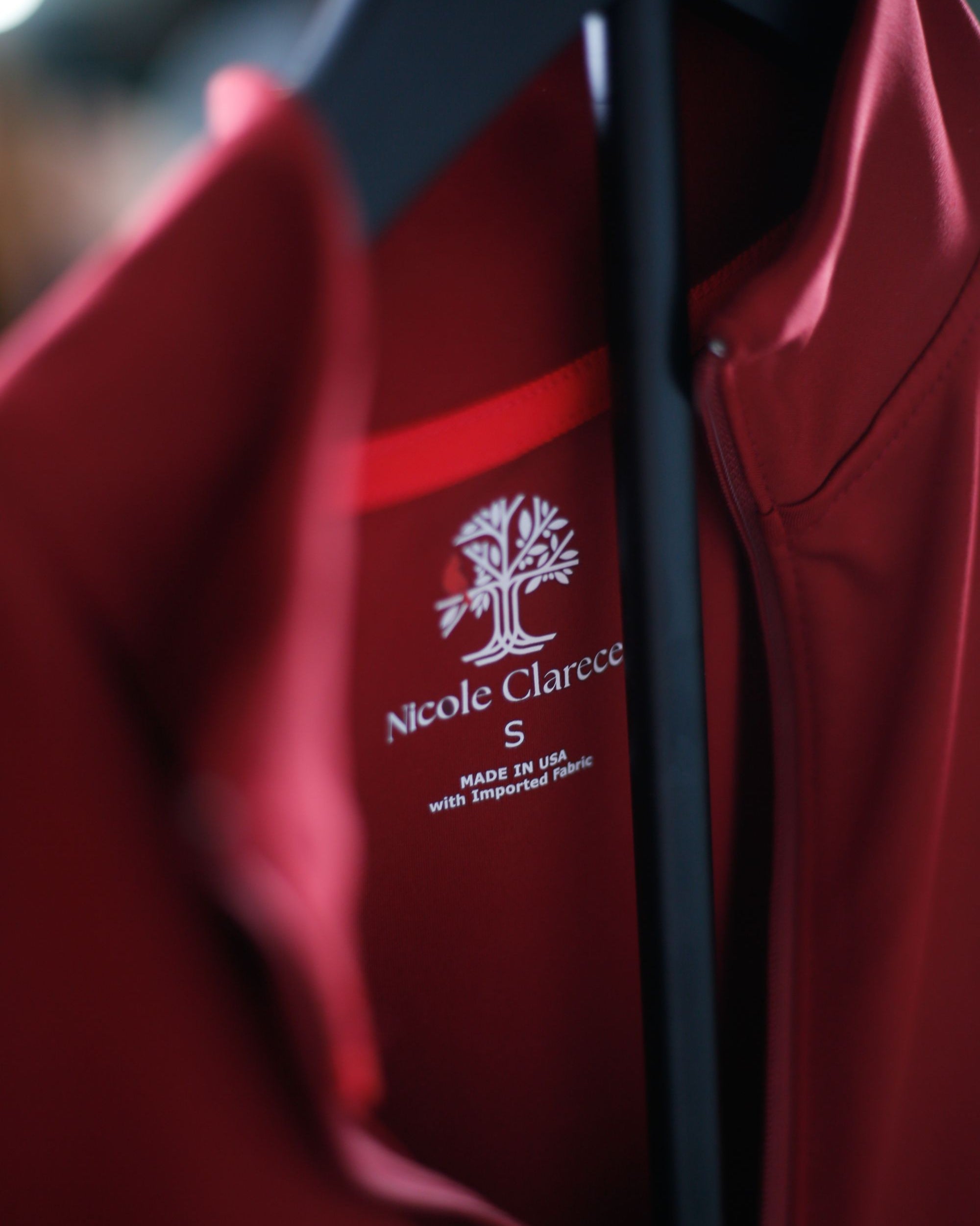 Detail shot of red Betty Quarter Zip Dress on a black hanger with a heat seal garment size and brand logo.
