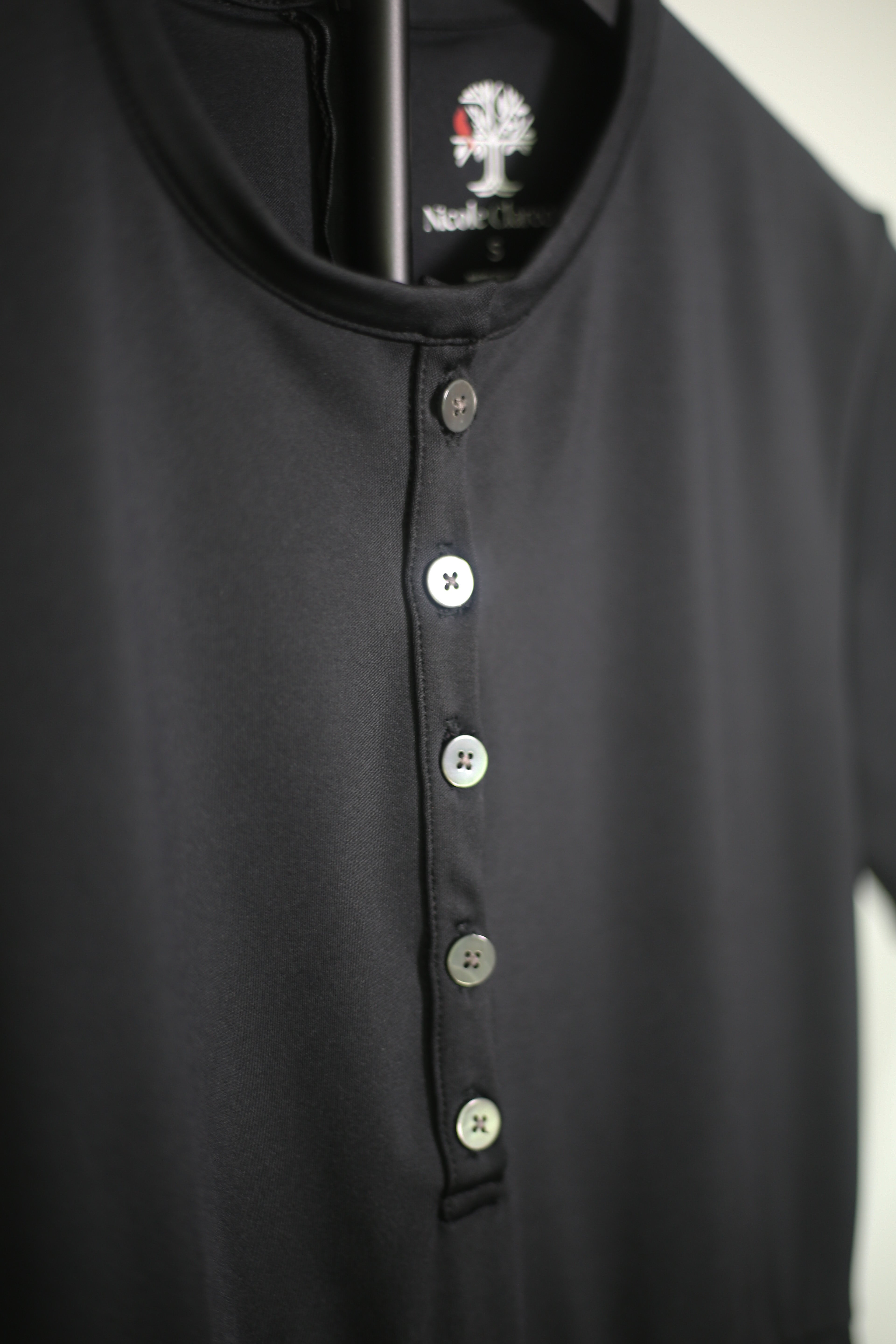 Detail shot of the Ace Henley Dress in black showcasing the five button neckline and high-quality performance fabrics.