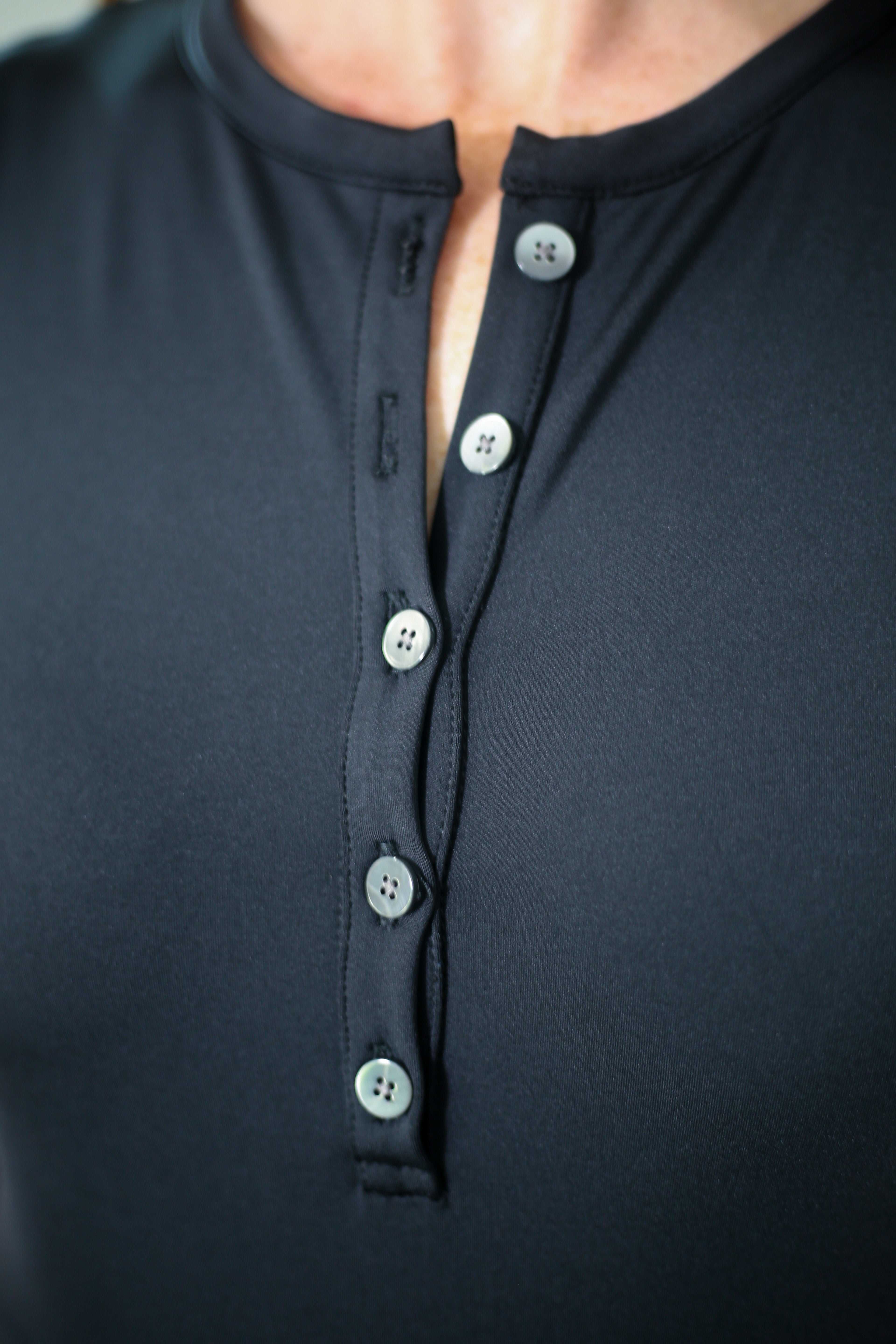Detail shot of woman wearing the Ace Henley Dress in black showcasing the five button neckline and high-quality performance fabrics.