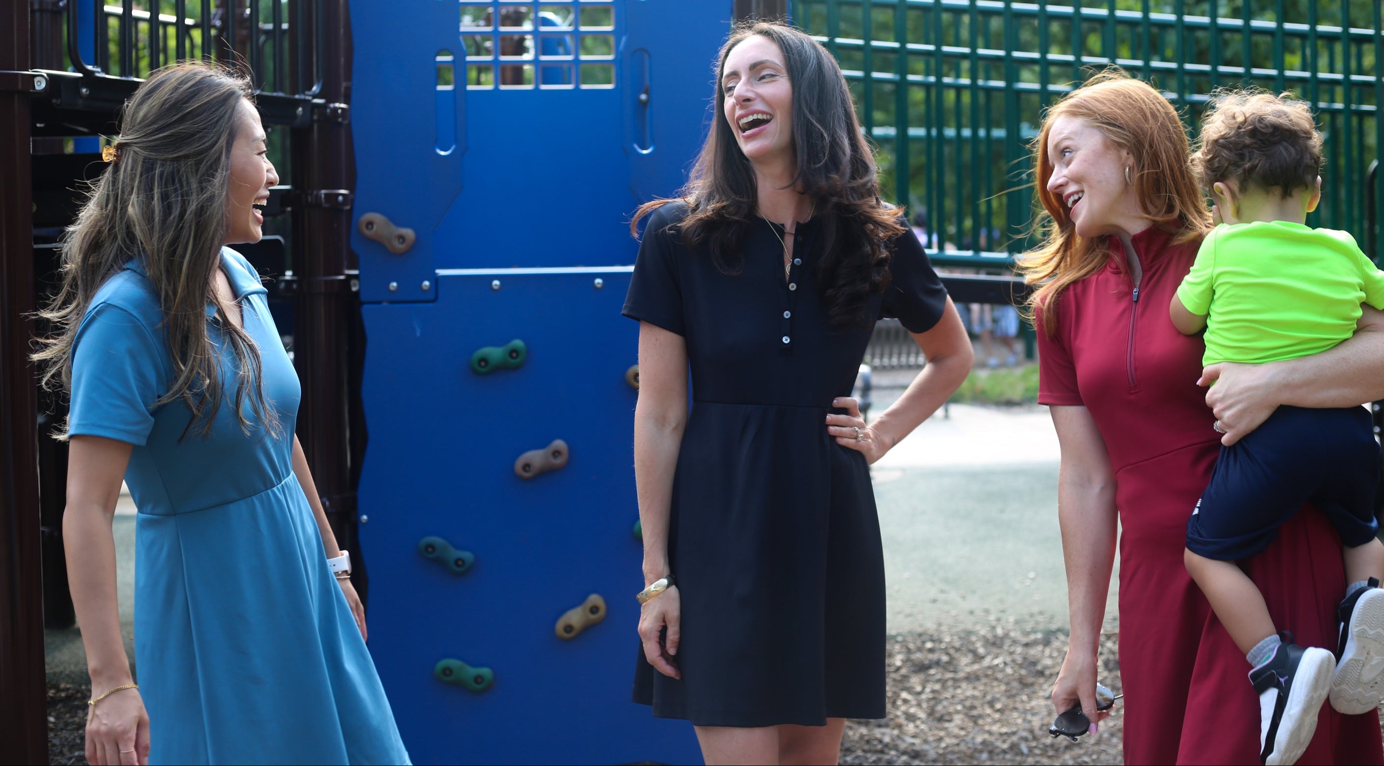 Three mothers are the park wearing Nicole Clarece dresses. One woman wears the Clarce Polo Dress in light blue, one wears the Ace Henley Dress in black and the third wears the Betty Quarter Zip Dress in red.