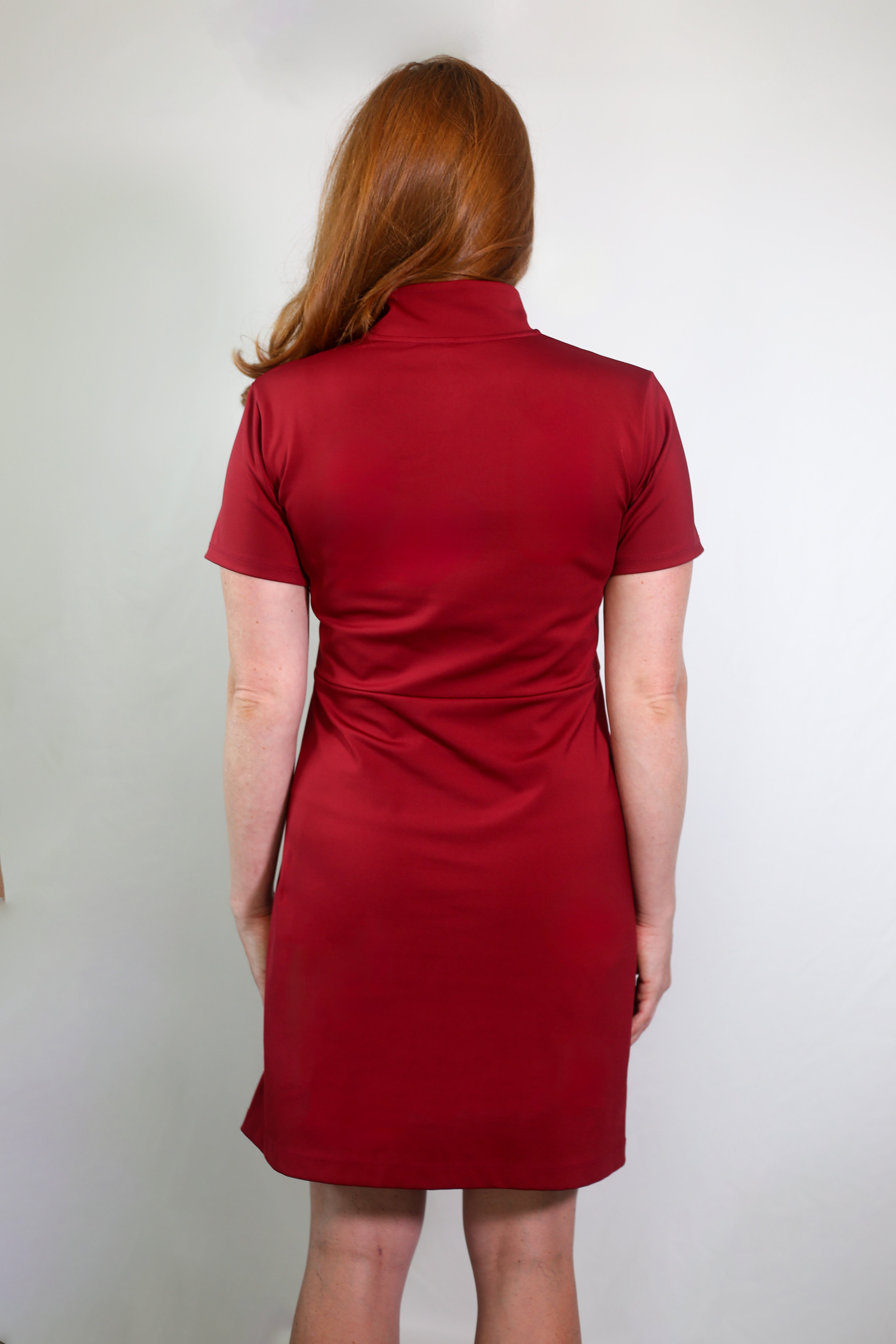 Woman wearing Betty Quarter Zip dress in red showing the back view. The dress is made from recycled performance fabrics and offering 4-way stretch, UV protection, and moisture-wicking for versatility, comfort and flexibility.