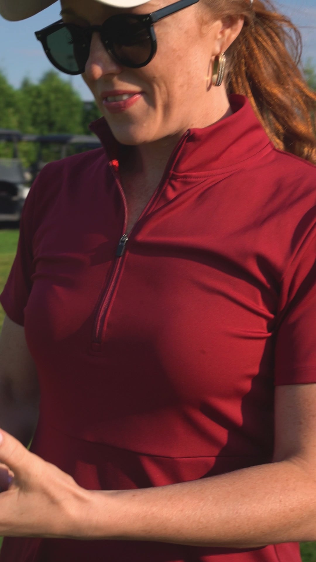 Two women golfing while wearing the red Betty Quarter Zip dress and the black Ace Henley dress showcasing their stretch, comfort, and versatility while on the move.