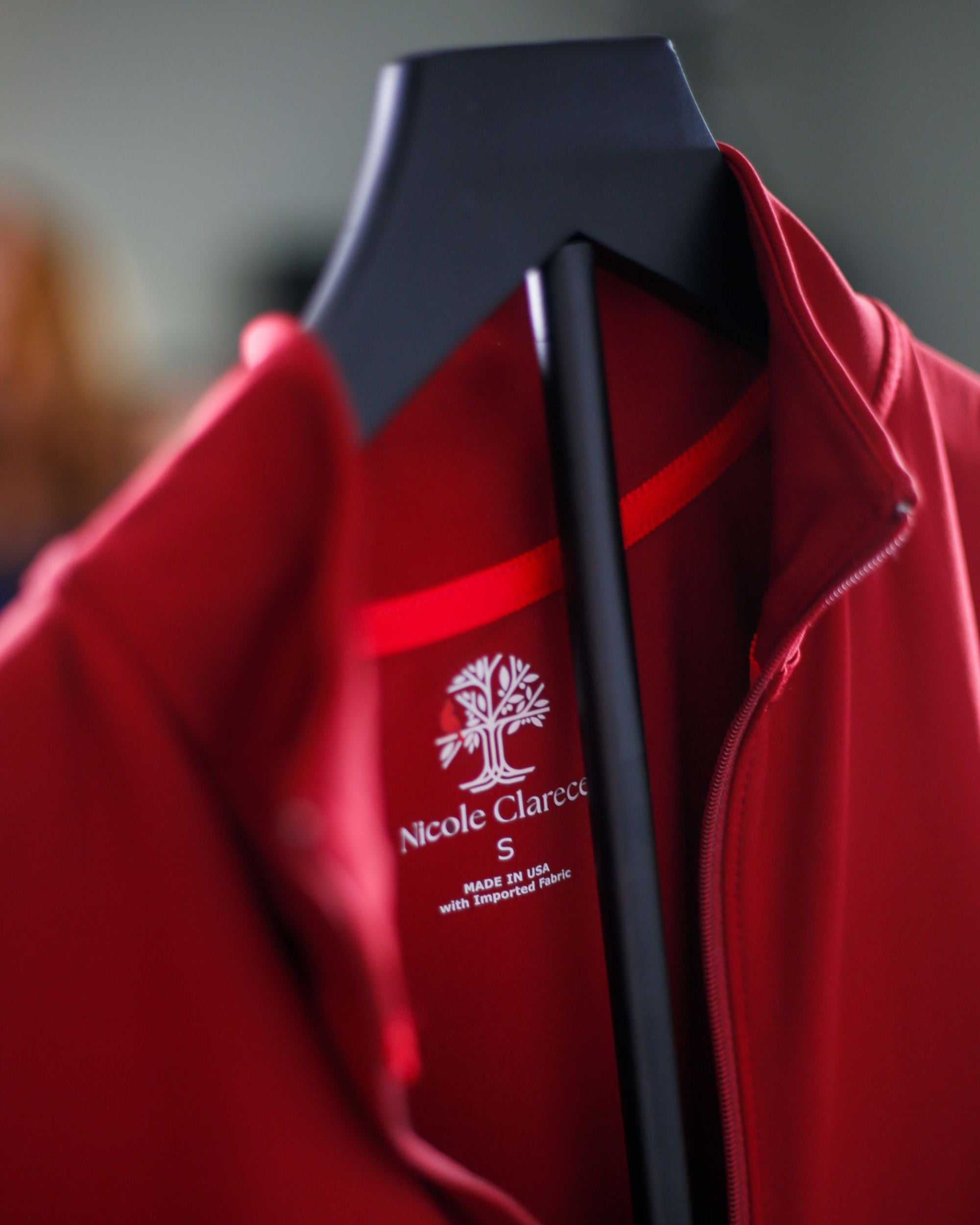 Detail shot of red Betty Quarter Zip Dress neckline, zipper, and printed heat seal with logo and dress size.