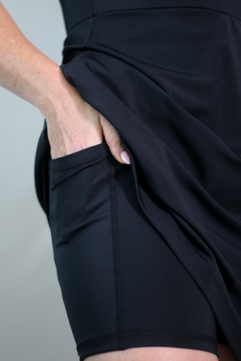 Detail shot of woman wearing the Ace Henley Dress in black showcasing the built in short with pockets.