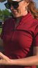 Two women golfing while wearing the red Betty Quarter Zip dress and the black Ace Henley dress showcasing their stretch, comfort, and versatility while on the move.